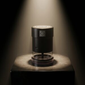 idoobi electric herb grinder on a marble block, black body with a clear grinding chamber