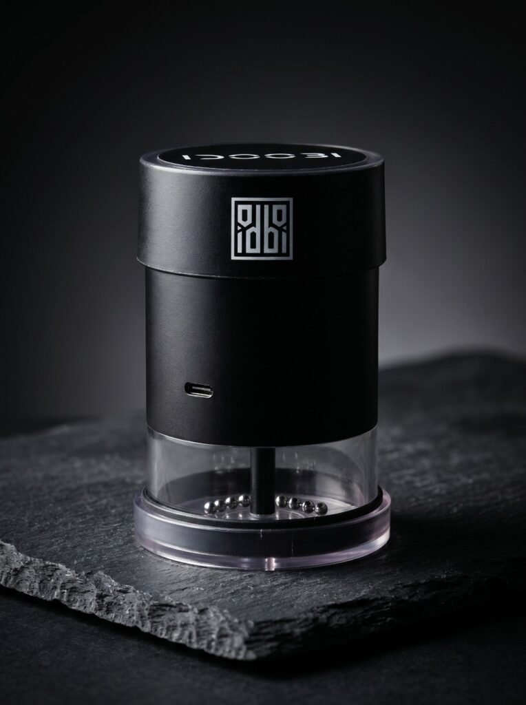 idoobi electric herb grinder on a slate slab, showing the steel chain in the clear chamber